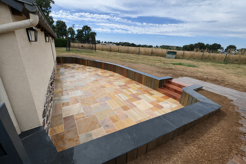 Après travaux — Création de terrasse en grès multicolore avec muret et escalier